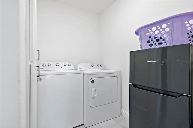 clothes washing area featuring light tile patterned flooring, washer and dryer, and laundry area