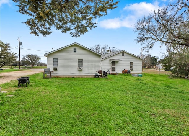 rear view of house with dirt driveway and a lawn