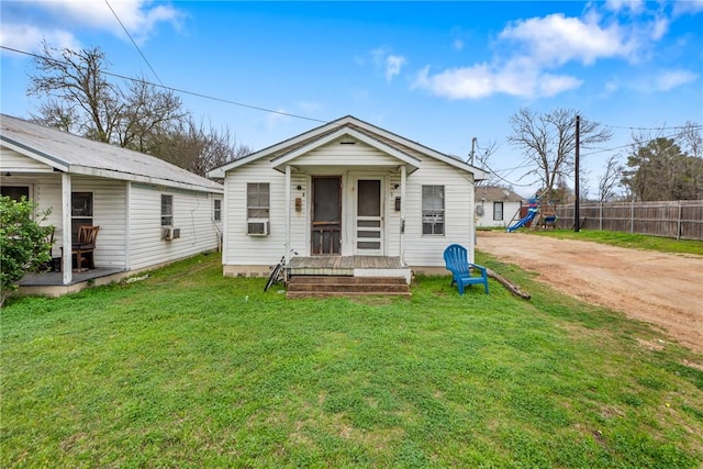 view of front facade with dirt driveway, fence, cooling unit, a front lawn, and a playground