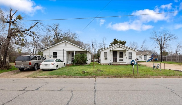 bungalow featuring a front lawn and a playground