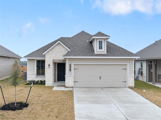 view of front of property featuring driveway, a shingled roof, stone siding, an attached garage, and a front yard