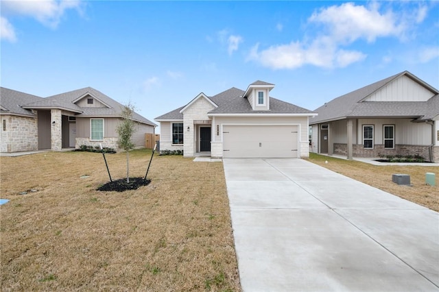 view of front of home with driveway, a garage, stone siding, roof with shingles, and a front yard