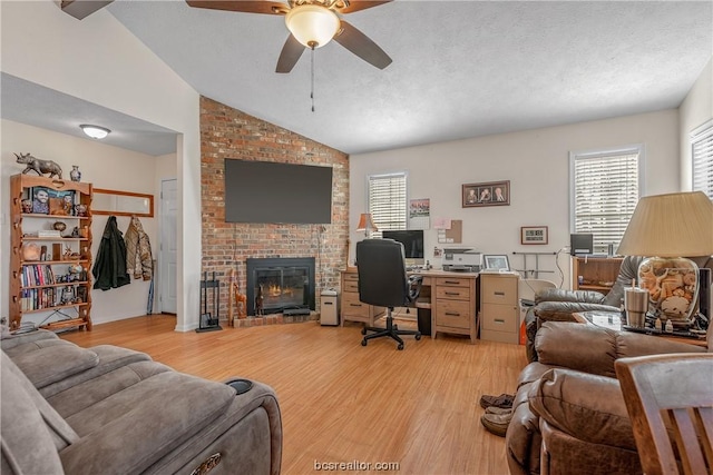 office with ceiling fan, high vaulted ceiling, a textured ceiling, a fireplace, and light wood-type flooring