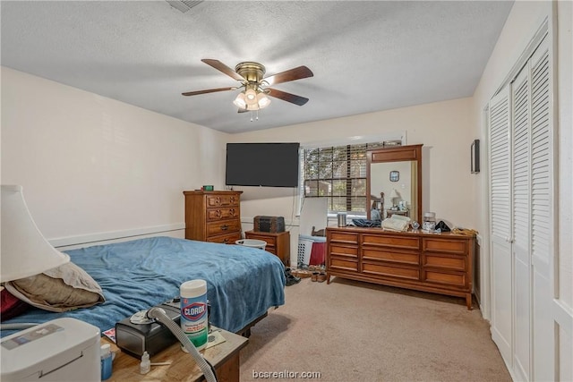 carpeted bedroom featuring ceiling fan, a textured ceiling, and a closet