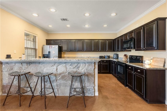 kitchen with crown molding, a breakfast bar, light stone countertops, black appliances, and light carpet