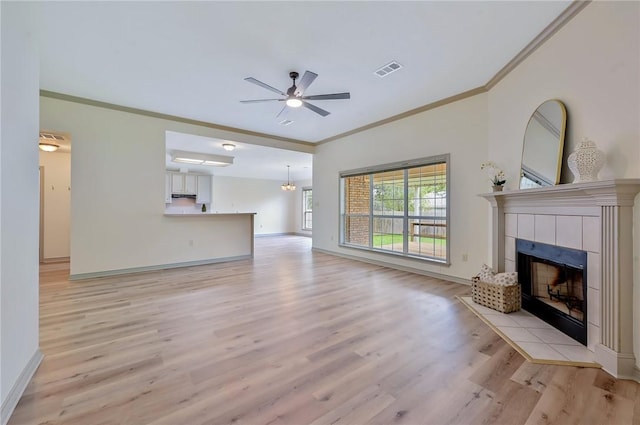 unfurnished living room featuring light hardwood / wood-style floors, ceiling fan, crown molding, and a tiled fireplace