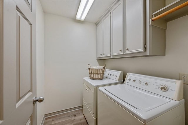 laundry area featuring cabinets, independent washer and dryer, and light hardwood / wood-style flooring