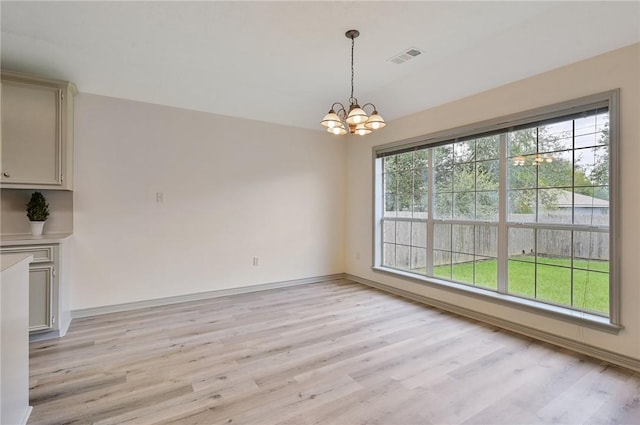 unfurnished dining area with light hardwood / wood-style flooring and a notable chandelier