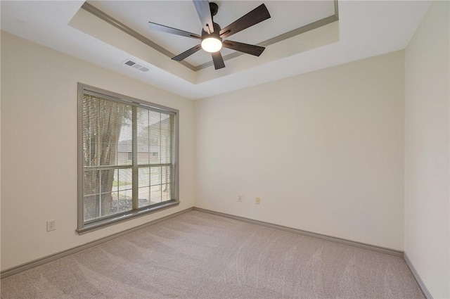 spare room featuring ceiling fan, a raised ceiling, and light colored carpet