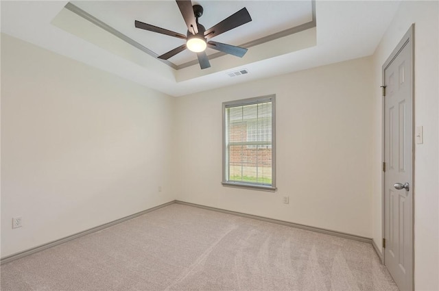 unfurnished room featuring a tray ceiling and light carpet