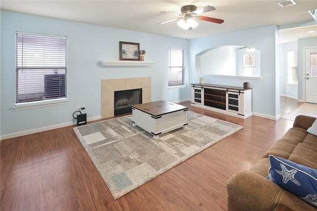 living room with ceiling fan, a fireplace, and wood-type flooring