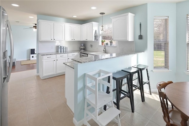 kitchen featuring hanging light fixtures, white cabinetry, stainless steel appliances, and kitchen peninsula