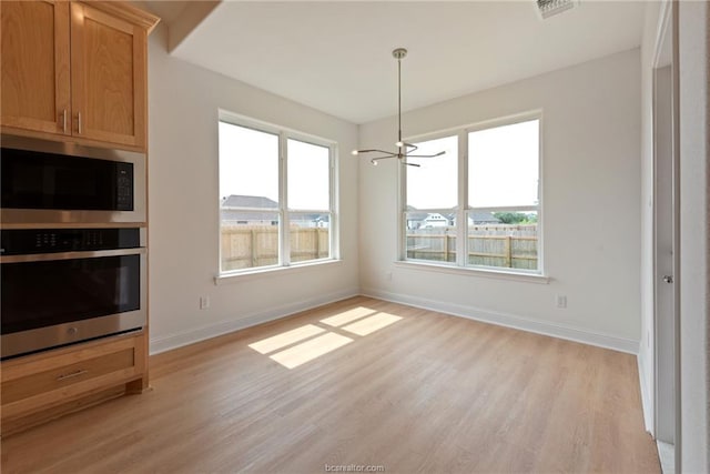 unfurnished dining area featuring an inviting chandelier, a healthy amount of sunlight, and light hardwood / wood-style floors