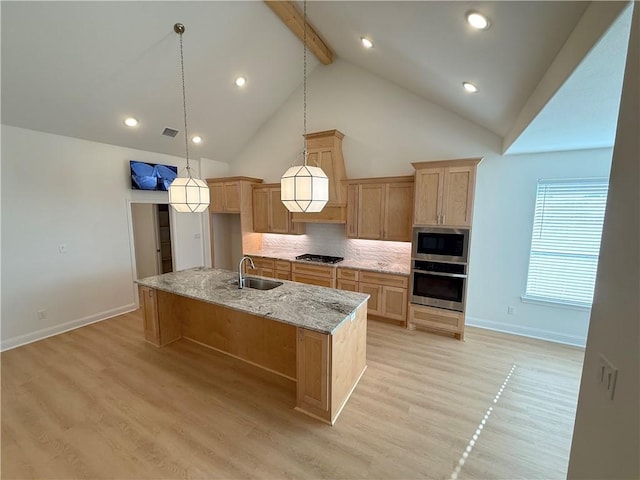 kitchen with pendant lighting, an island with sink, sink, stainless steel appliances, and light hardwood / wood-style flooring