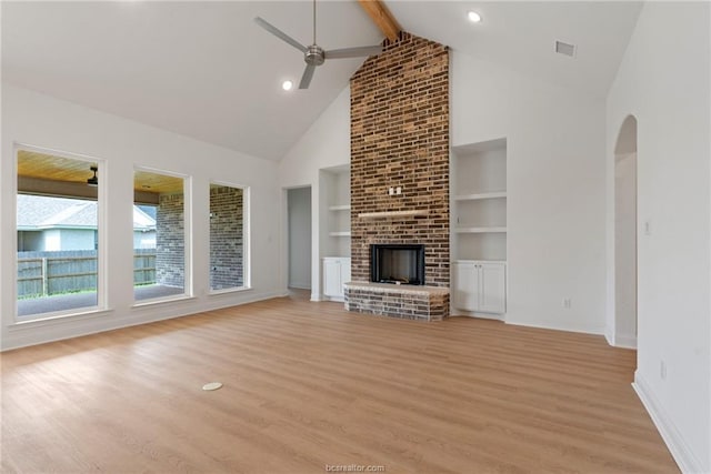 unfurnished living room with a brick fireplace, light hardwood / wood-style flooring, built in features, ceiling fan, and beam ceiling