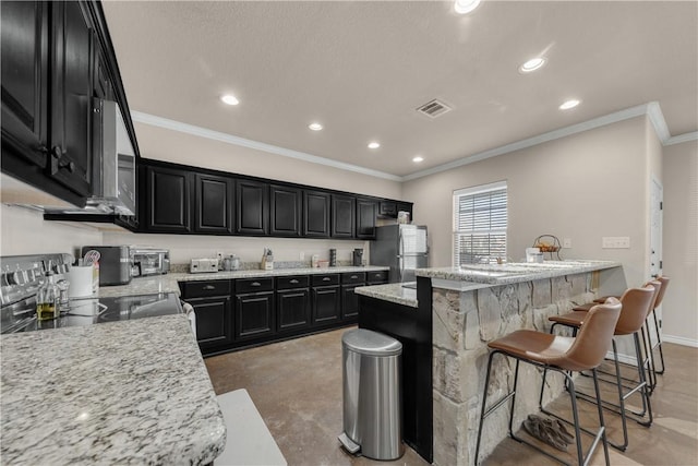 kitchen featuring a kitchen bar, light stone countertops, crown molding, and stainless steel appliances