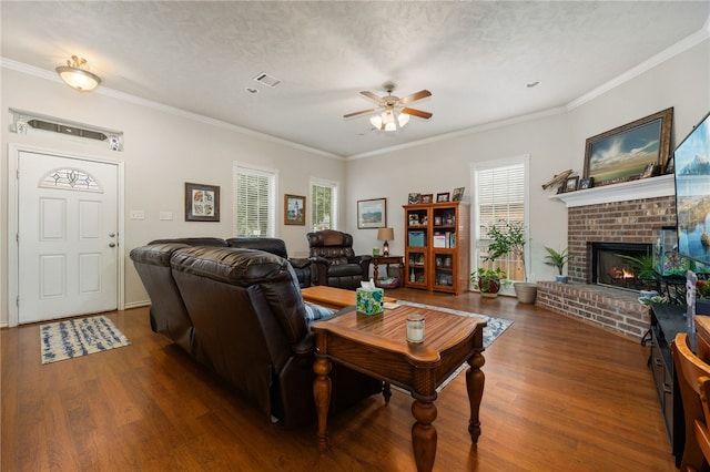 living room featuring dark wood-type flooring, a fireplace, ornamental molding, and a textured ceiling