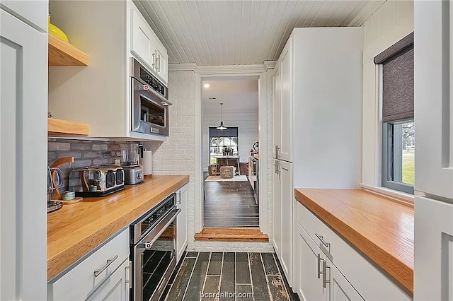 bar featuring wood counters, white cabinetry, oven, dark wood-type flooring, and hanging light fixtures