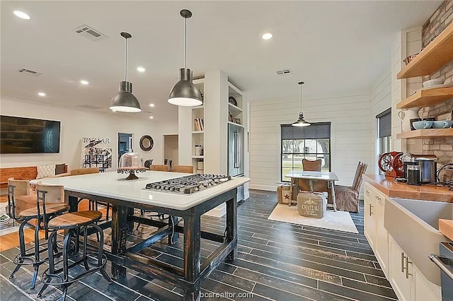 kitchen with dark wood-type flooring, hanging light fixtures, a breakfast bar, and high end fridge