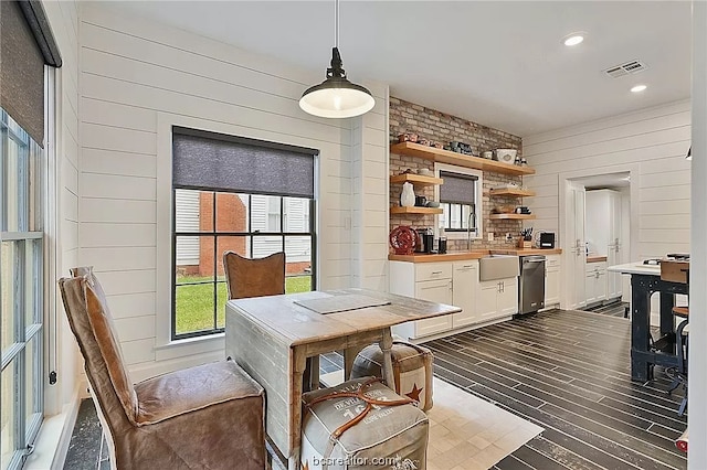 dining space featuring hardwood / wood-style flooring, wooden walls, and sink