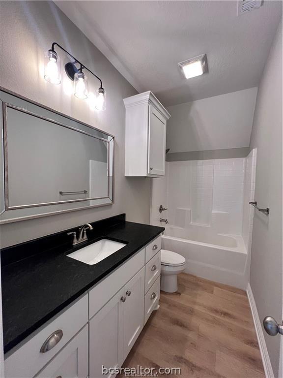 2126 Mountain Wind Loop, Bryan, TX 77807 - full bathroom featuring wood finished floors, vanity, shower / bath combination, and lofted ceiling