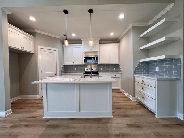 kitchen featuring white cabinetry, stainless steel appliances, tasteful backsplash, light hardwood / wood-style flooring, and an island with sink