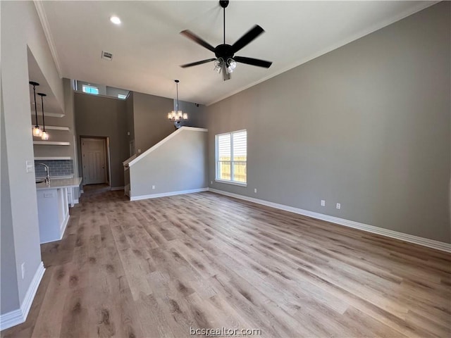 unfurnished living room with sink, light wood-type flooring, and crown molding