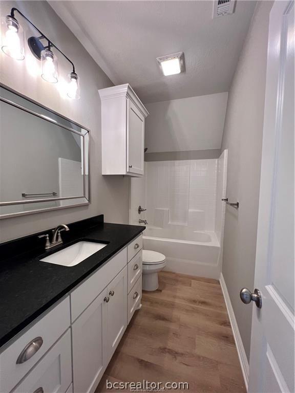 2126 Mountain Wind Loop, Bryan, TX 77807 - full bathroom with wood finished floors, vanity, lofted ceiling, and shower / tub combination