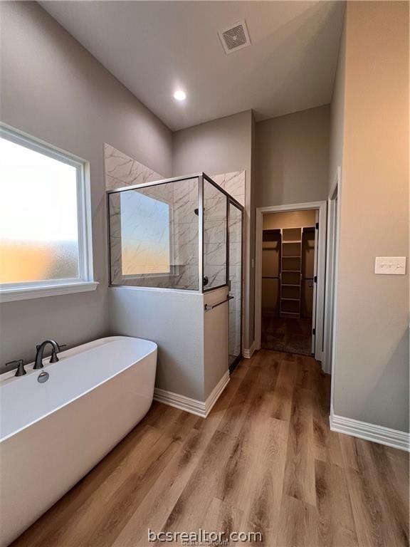 2126 Mountain Wind Loop, Bryan, TX 77807 - full bathroom with a walk in closet, a stall shower, a freestanding bath, and wood finished floors