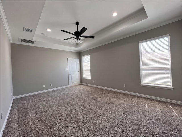 empty room with ceiling fan, ornamental molding, carpet floors, and a tray ceiling