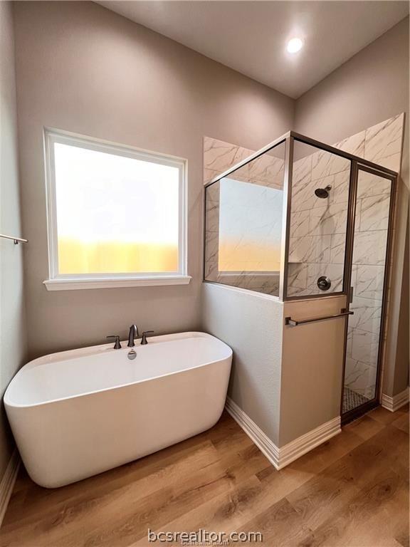 bathroom with hardwood / wood-style floors and separate shower and tub