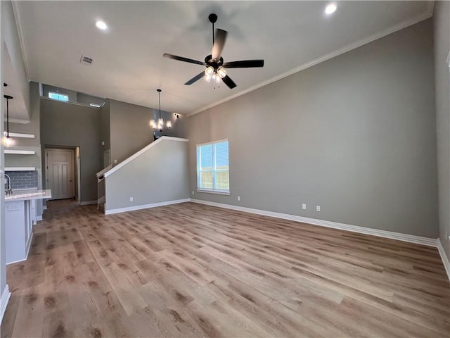 unfurnished living room with ornamental molding, ceiling fan with notable chandelier, and light wood-type flooring