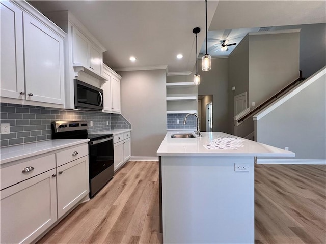 kitchen with a kitchen island with sink, hanging light fixtures, sink, white cabinetry, and stainless steel appliances