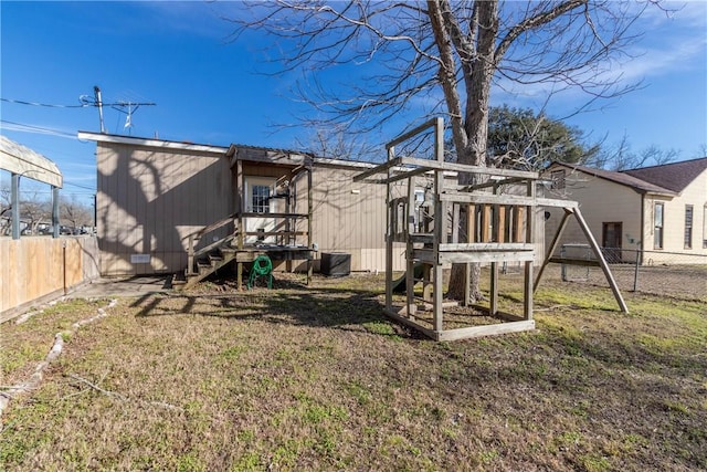 rear view of house with a lawn, fence, and a playground