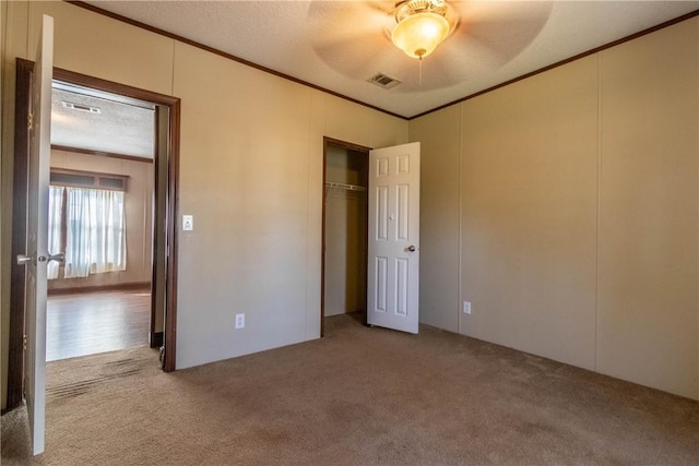 unfurnished bedroom featuring ornamental molding, carpet flooring, and visible vents