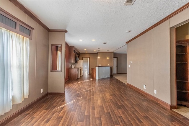 unfurnished living room with a textured ceiling, ornamental molding, and dark wood finished floors