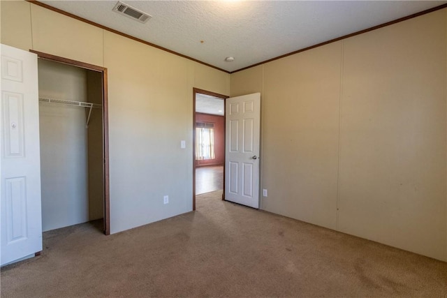 unfurnished bedroom with ornamental molding, light colored carpet, visible vents, and a textured ceiling