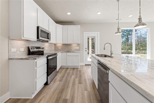 kitchen featuring pendant lighting, sink, appliances with stainless steel finishes, white cabinetry, and a wealth of natural light