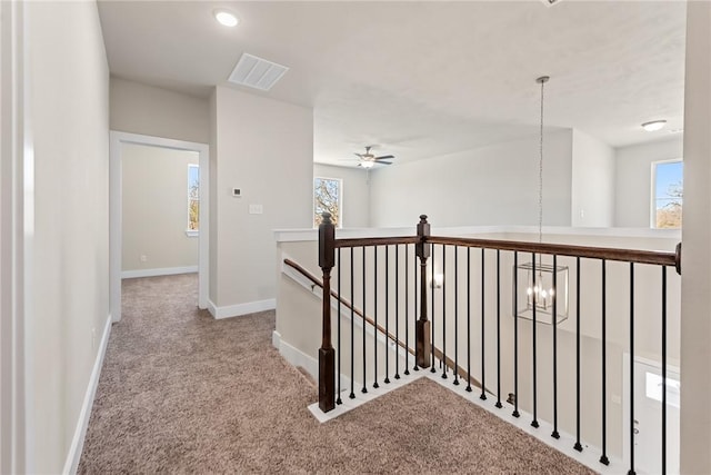 hallway featuring light carpet and a chandelier