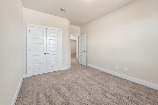 unfurnished bedroom featuring light colored carpet and a closet