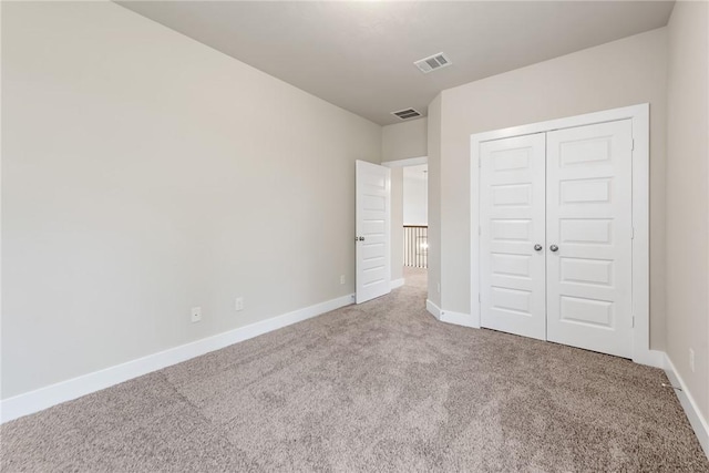 unfurnished bedroom with a closet and light carpet