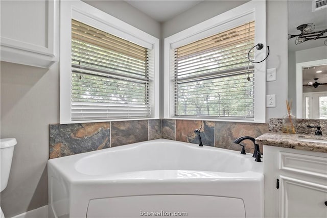 bathroom featuring ceiling fan, toilet, vanity, and a wealth of natural light