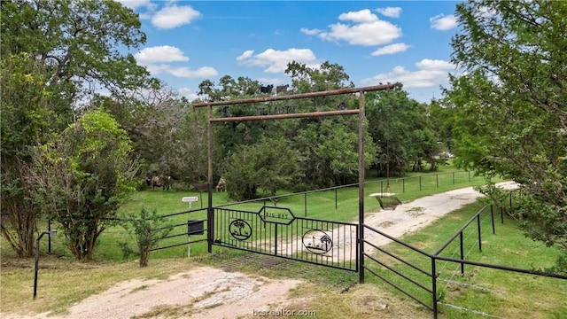 view of gate with a lawn and a rural view