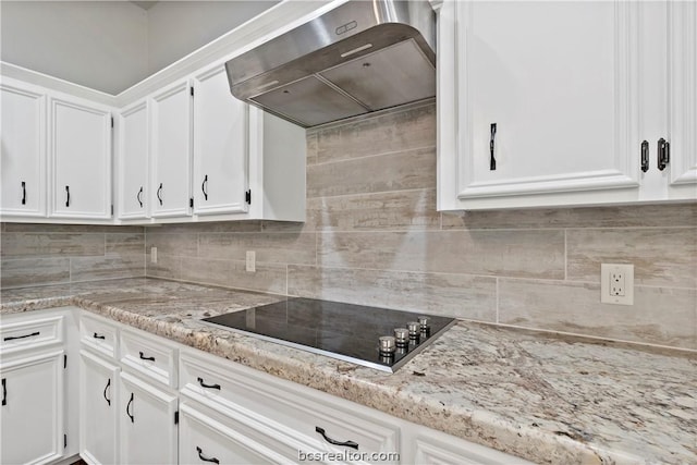 kitchen featuring black electric stovetop, tasteful backsplash, white cabinetry, and wall chimney exhaust hood