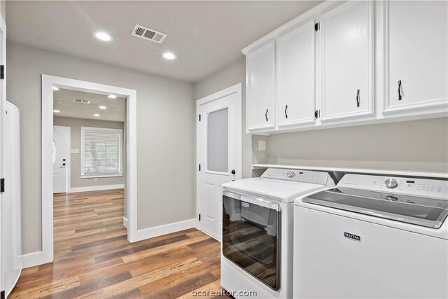 washroom featuring hardwood / wood-style floors, cabinets, and washing machine and dryer