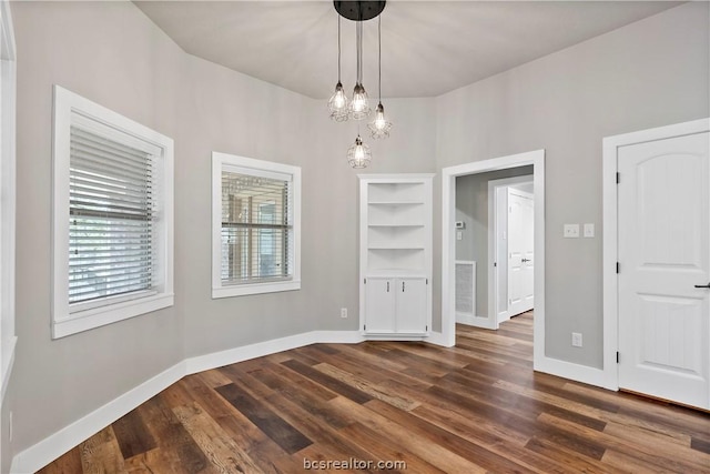 unfurnished dining area with dark hardwood / wood-style flooring and a chandelier