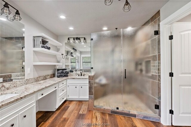 bathroom featuring hardwood / wood-style floors, vanity, and a shower with door