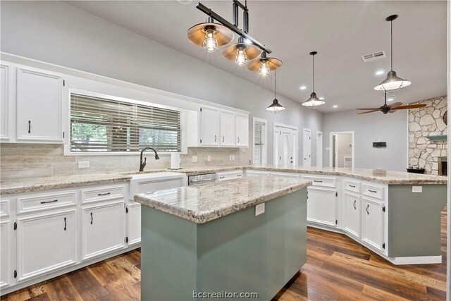 kitchen with white cabinets, sink, hanging light fixtures, dark hardwood / wood-style floors, and a kitchen island