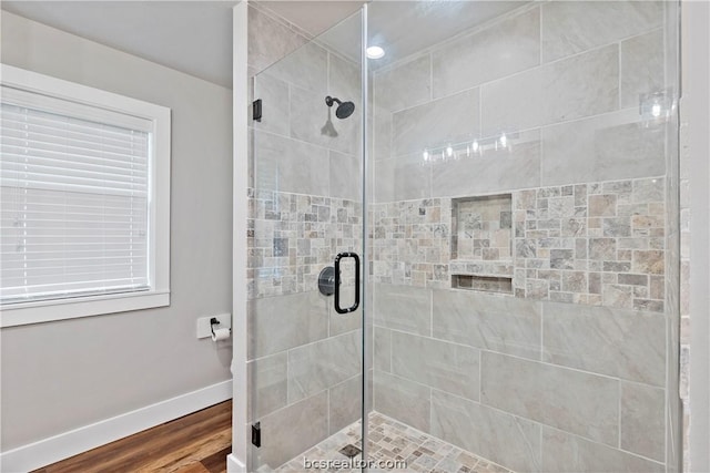 bathroom with a shower with door, plenty of natural light, and hardwood / wood-style flooring