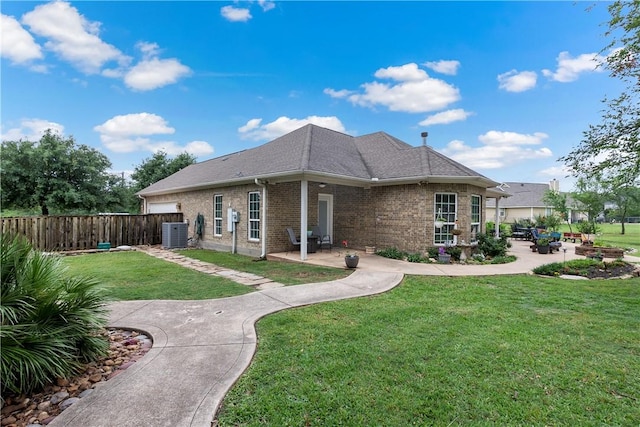 rear view of house with central air condition unit, a patio area, a yard, brick siding, and fence